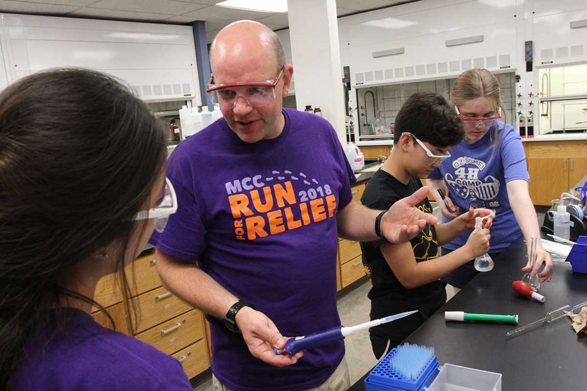 Students and faculty members in a science lab wearing safety goggles
